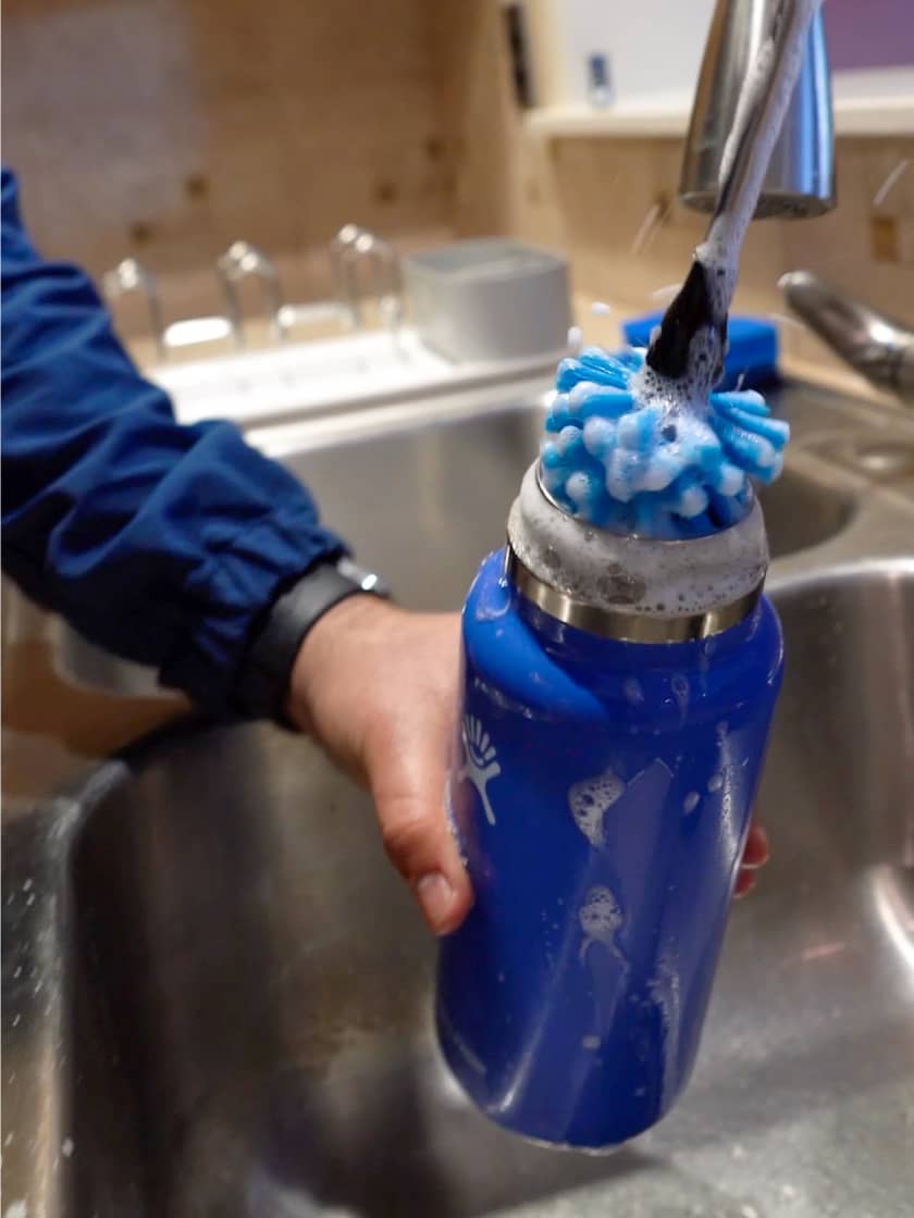 A Wide Mouth Hydro Flask being cleaned with soap and water and a Hydro Flask Bottle Brush.