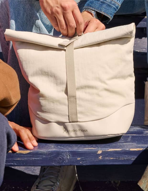 Hydro Flask Oat colored Carryout&trade; Lunch Rolltop sitting on school bleachers
